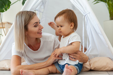 Young mother and little daughter spend time together in a wigwam at home © splitov27