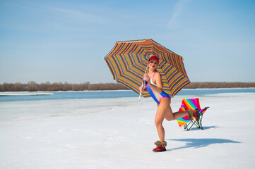 Caucasian woman in a swimsuit sunbathes on the snow in winter.