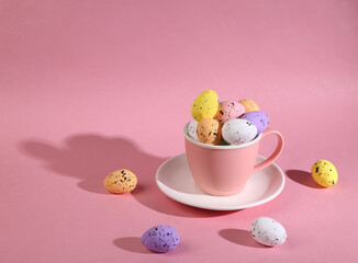 Ceramic cup with colored eggs on a bright pink background. Minimal Easter still life