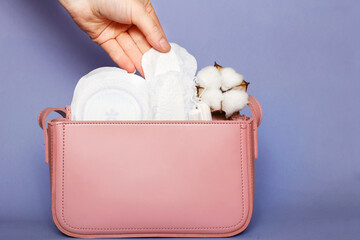 Women's hand takes out panty liner from pink cosmetic bag with tampons and feminine sanitary pads