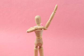 Wooden puppet singing into microphone on pink background
