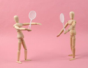 Two puppets with tennis rackets play tennis on pink background