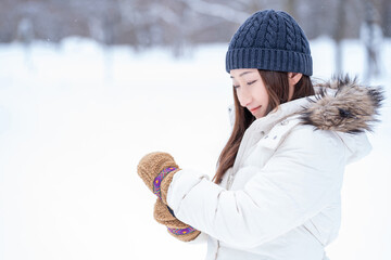 雪の中で手袋をする女性（冬・笑顔）
