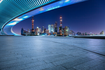 Panoramic skyline and modern commercial buildings with empty square floor in Shanghai at night,...