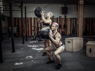 Muscular athletic women train with medicine balls in a modern gym. Cross fit, functional training