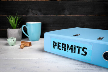 PERMITS. Coffee mug, document folder and office supplies on the desk