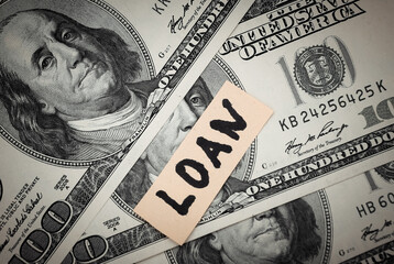 Loan word on hundred dollar bills on white background