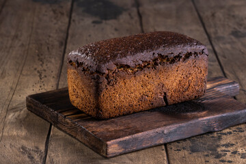 Freshly baked rye bread on wooden board. Wooden background.