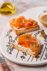 Two open sandwich, toast with smoked salmon, cream cheese, watercress, on white concrete table. Morning healthy breakfast with fish. side view, close up. clean eating.