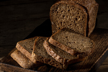 Bread, traditional homemade bread cut into slices on a rustic wooden background, close-up.