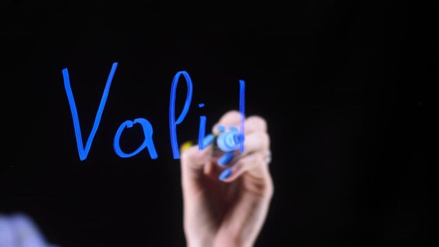 validators close-up on a black background. The girl writes words with a blue marker.