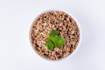 Bowl of buckwheat flakes isolated on white background, top view