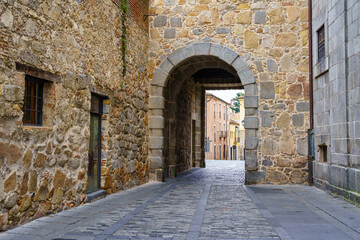 Fototapeta na wymiar Pedestrian alley in medieval town with stone arch under old building. Ávila, Spain.
