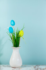 Vase with grass and Easter eggs, space for text, green background.