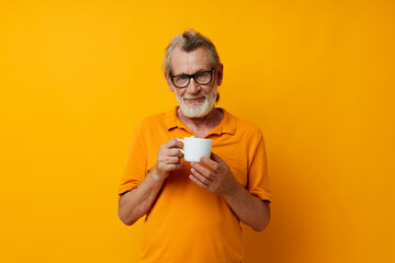 elderly man in a yellow t-shirt white mug yellow background