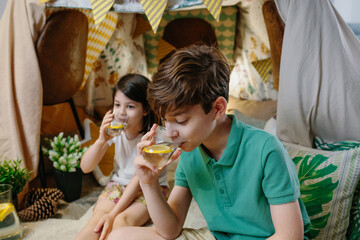 Boy drinking homemade lemonade with his sister while camping at home