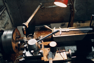 Turner worker working on old lathe machine at factory