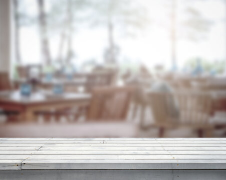 Empty white wooden table top with blur image of a restaurant in the hotel outdoor with natural wood in a perspective background, copy space for your text ready for product promotion display montage