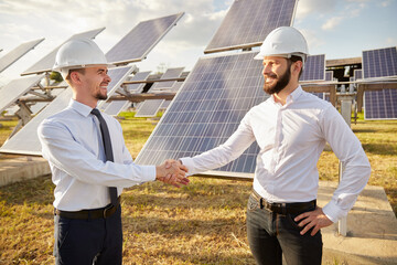 Engineers shaking hands in field with solar panels