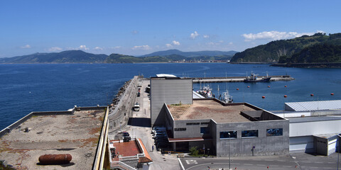 Paisaje marítimo con puerto y acantilados. 