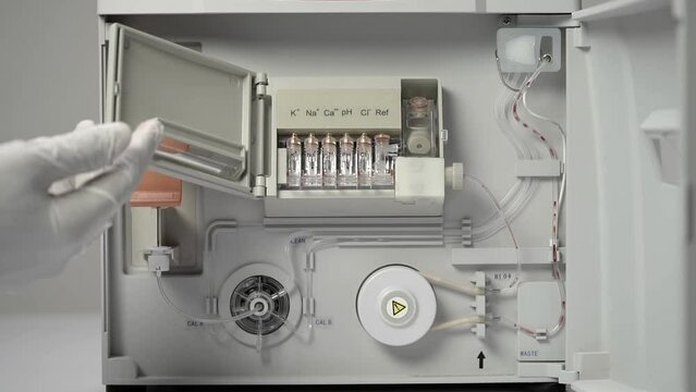 Hand In Glove Opens Locking Device Revealing Electrodes In Place. Automatic Electrolyte Analyzer Feeding Specimen For Analysis. close up