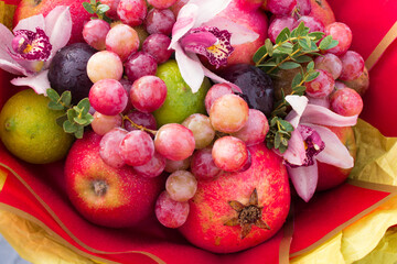 Fruity edible bouquet of red apples with plums, grapes, pomegranate, lime and pink living orchids. High quality photo