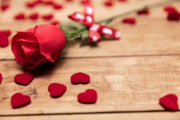 red rose and fabric heart on wooden background.