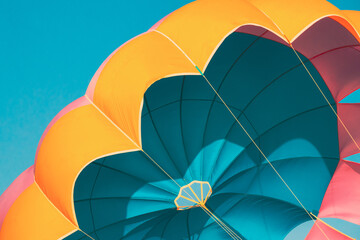 Close Multi-colored Parachute For Parasailing On Background Of Blue Sky. Close Multi-colored Parachute For Parasailing On Background Of Blue Sky.