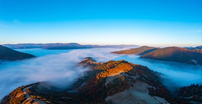 Thick fog among peaks of high autumn mountains at sunrise © YouraPechkin