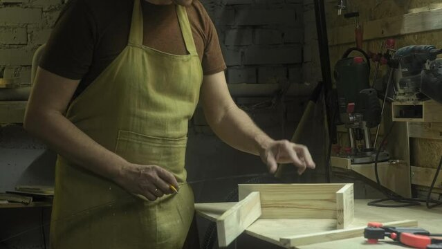 A man in a woodworking workshop measures the material with a ruler, home workshop business furniture production.