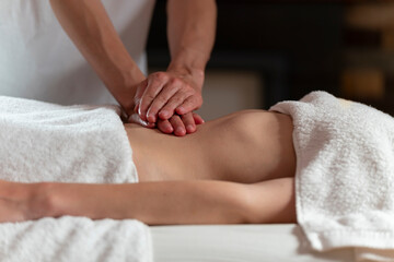 A masseuse woman doing an oil massage to another woman on the stomach