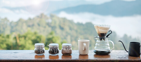arabica coffee brewing by Vintage coffee drip equipment set on wooden table in the morning with mountain and nature background