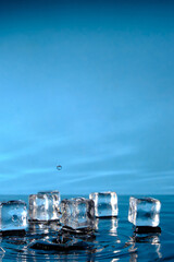 Ice cubes in bright blue water and a splash of raindrops.