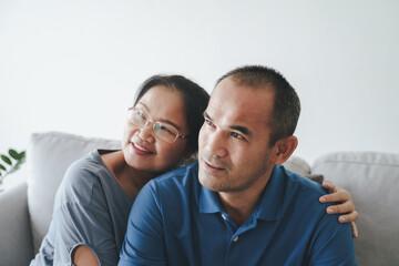 Obraz premium Portrait of Asian mature couple sitting in the living room. wife and husband hugging, holding hand with happiness and cheerful. Love, safety, and insurance family concept.