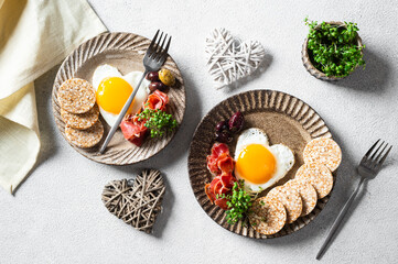 Romantic Breakfast on Women's Day - fried eggs in the shape of a heart and olives. Healthy breakfast. Rice cakes with eggs and hamon. Romantic breakfast. Top view.