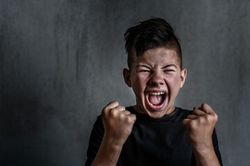Teen boy screaming in anger on dark background. The problem of helping teenagers in a difficult period