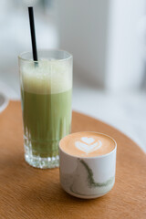 Matcha and Cup of cappuccino with latte art on wooden table in cafe. Concept of easy breakfast. Food banner