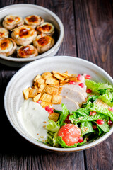 Traditional caesar salad in a white bowl on a old dark rustic table. Selected focus.