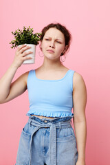 beautiful woman in a blue T-shirt and shorts a flowerpot pink background unaltered