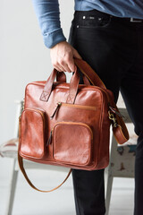 Side view of man in a blue sweater with red leather briefcase. Retro style. Unisex bag for sale.