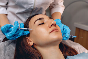 Cosmetic procedure close-up. The cosmetologist's hands hold syringes. Doing the anti aging procedure.