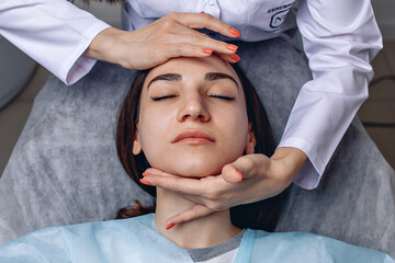 Refreshing and relaxing for the skin of the face. A cosmetologist provides a service in the form of a facial massage to a young girl in close-up.