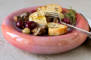 plate with baked camembert with champignons, grapes, rosemary and garlic on the table