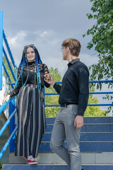 Obraz premium A young gallant man helps a woman down the stairs.