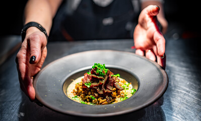 chef hand holding plate with food on kitchen in restaurant