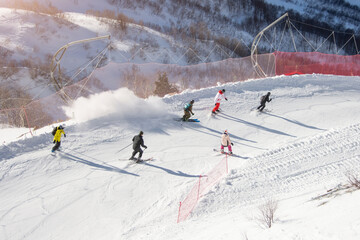 Skiers and snowboarders slide down the slope of the slope of the ski resort.