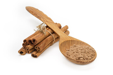 Cinnamon powder in wooden spoon and bundle of cinnamon sticks