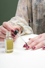Woman applying cuticle oil on the nails. Hand skin care at home with moisturizing oil. Beauty, style, makeup, fashion, lifestyle concept.