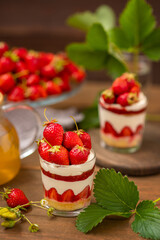 Strawberry dessert in a glass with a decor of cut strawberries standing on a wooden background
