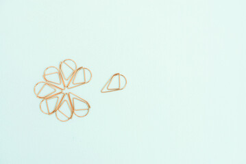 copper color office paperclips on light blue background
